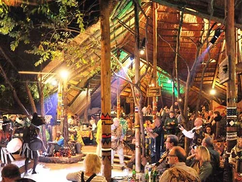 Performers and diners inside the illuminated thatched Boma venue